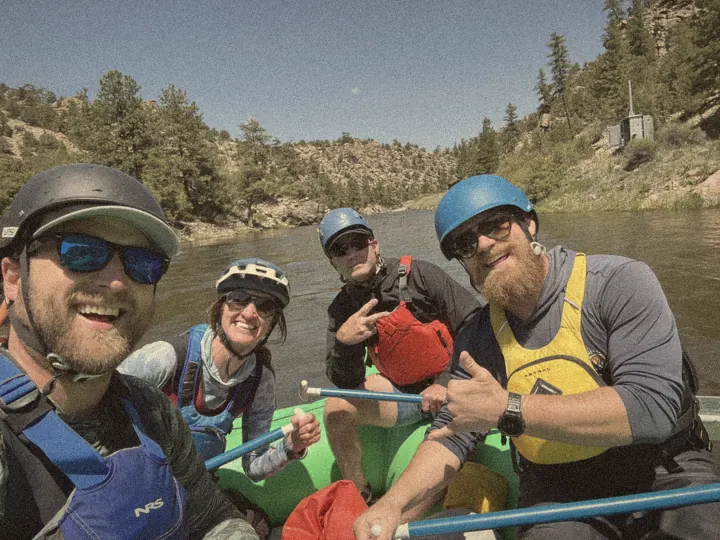 Four friends in helmets and life jackets grinning in a raft on the Arkansas River in Browns Canyon